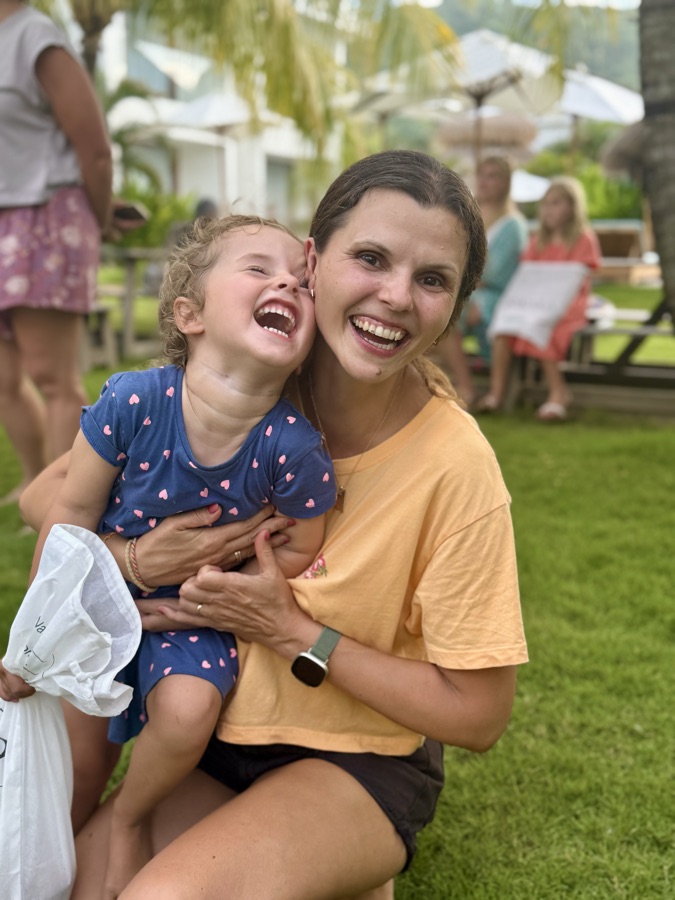 Anna lacht mit ihrer Tochter im Arm